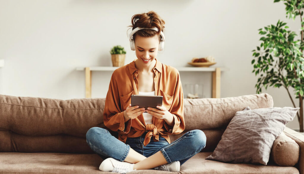 Digital patient engagement tools: happy woman wearing headphones and using a tablet